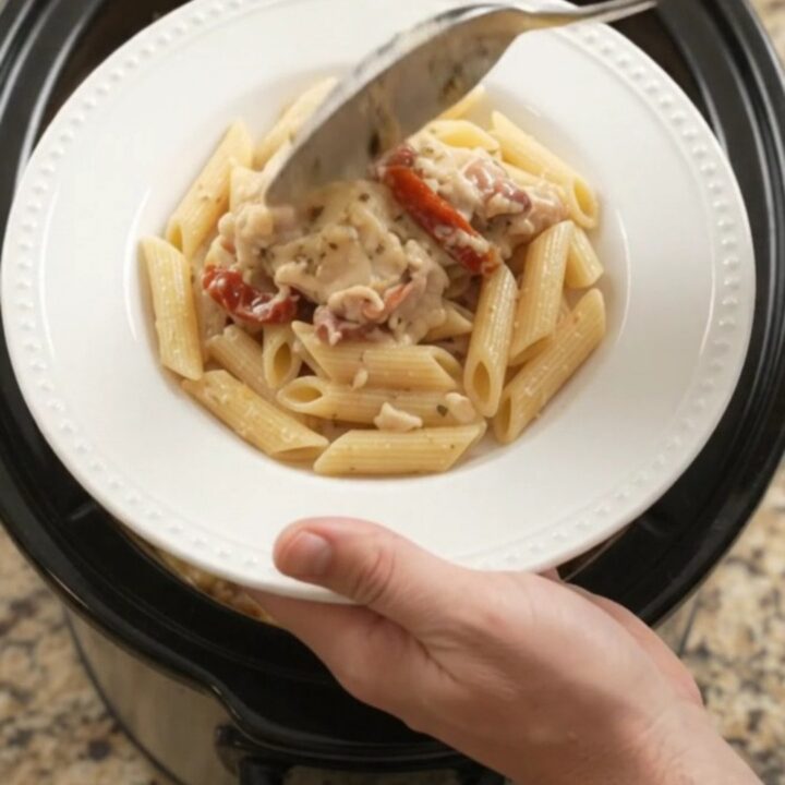 Slow cooker full of creamy mozzarella sun-dried tomato chicken thighs, bubbling with cheese and herbs