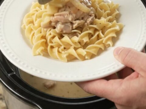 Creamy Parmesan French onion chicken thighs in a slow cooker, topped with sweet onions and a velvety white sauce.