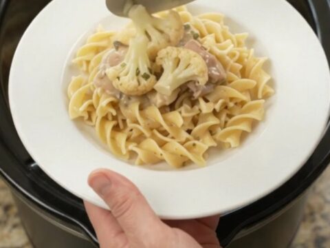 Creamy slow-cooker chicken and cauliflower in a white bowl with a spoon