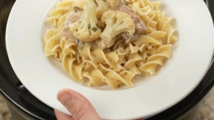 Creamy slow-cooker chicken and cauliflower in a white bowl with a spoon