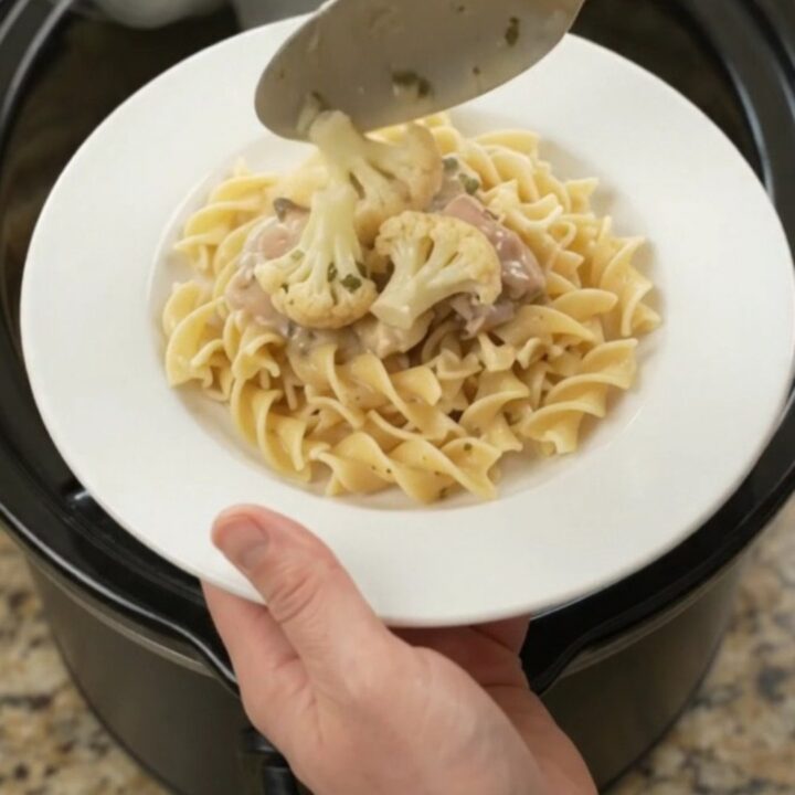 Creamy slow-cooker chicken and cauliflower in a white bowl with a spoon