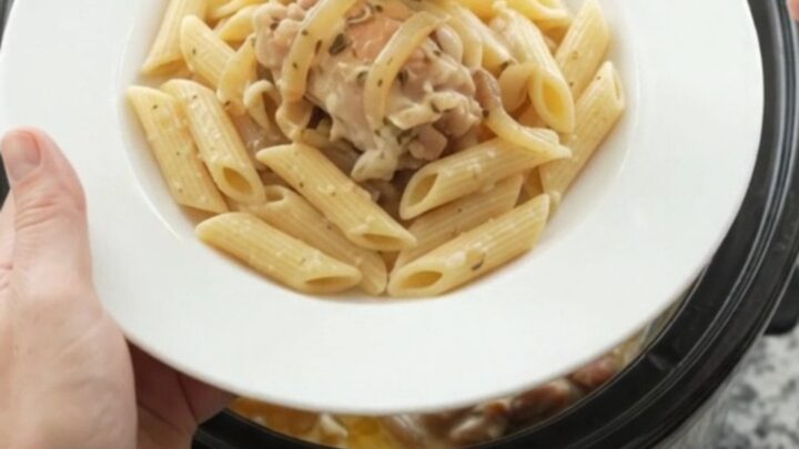Slow cooker filled with creamy mozzarella French onion chicken, garnished with fresh herbs