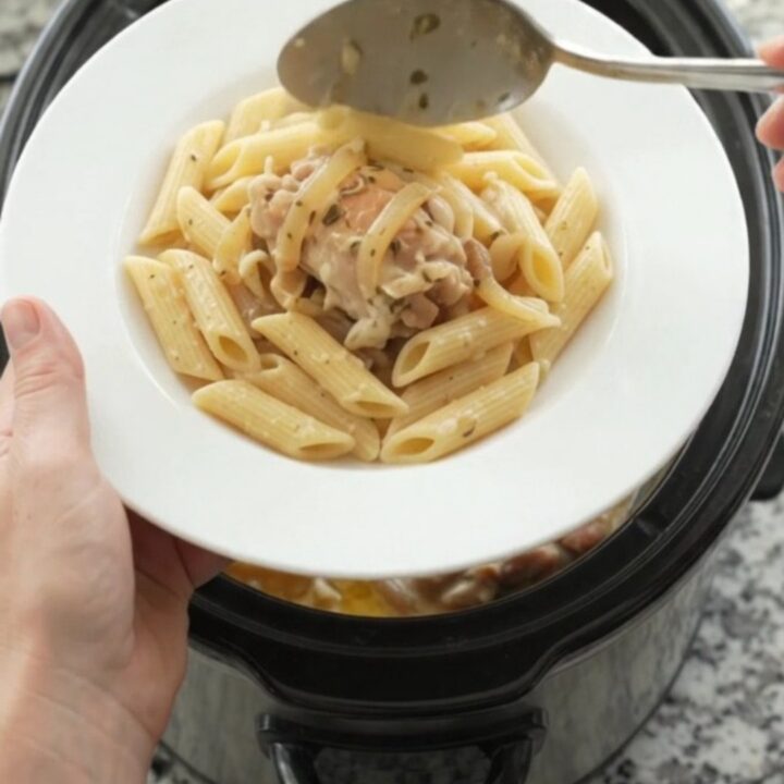 Slow cooker filled with creamy mozzarella French onion chicken, garnished with fresh herbs