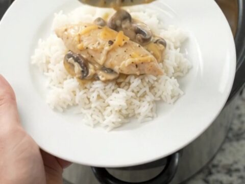 Golden Cheddar Mushroom Chicken Tenders bubbling in a slow cooker, with creamy sauce and mushrooms visible.