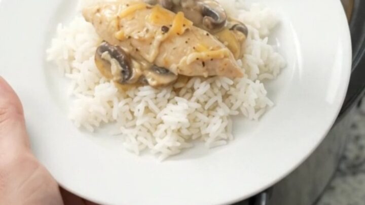 Golden Cheddar Mushroom Chicken Tenders bubbling in a slow cooker, with creamy sauce and mushrooms visible.