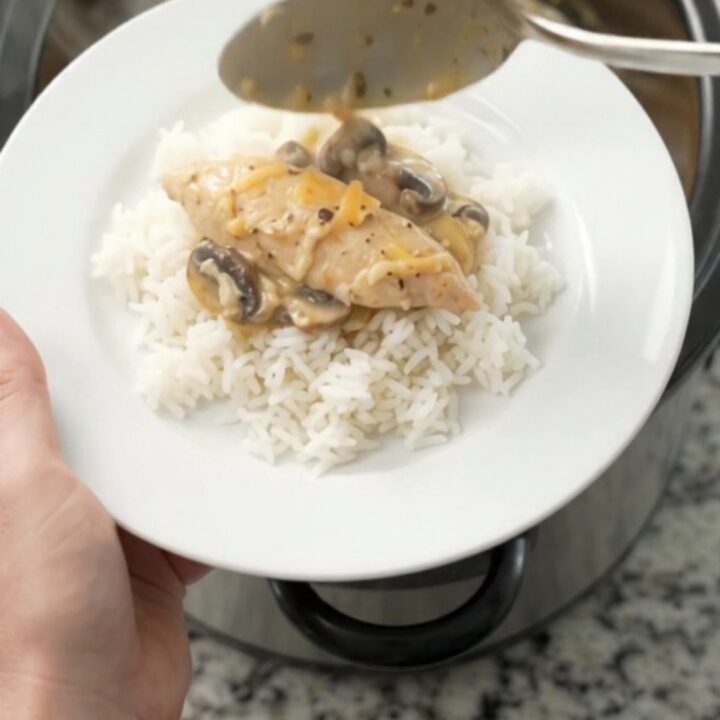 Golden Cheddar Mushroom Chicken Tenders bubbling in a slow cooker, with creamy sauce and mushrooms visible.