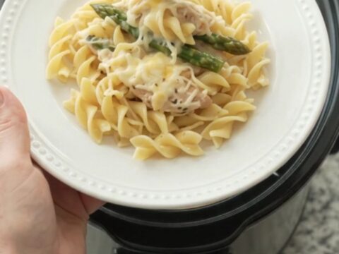 Slow cooker filled with creamy Parmesan asparagus chicken tenders, ready to serve