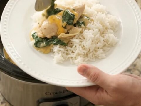 Slow cooker filled with creamy cheddar chicken, spinach, and artichokes