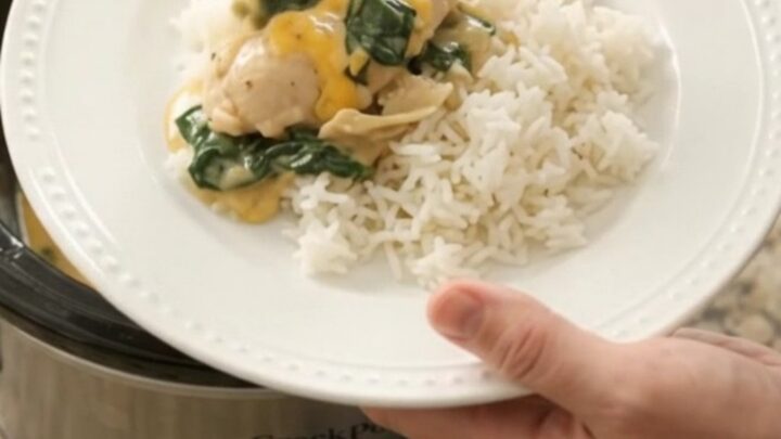 Slow cooker filled with creamy cheddar chicken, spinach, and artichokes