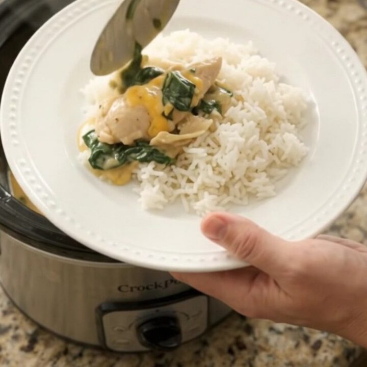 Slow cooker filled with creamy cheddar chicken, spinach, and artichokes