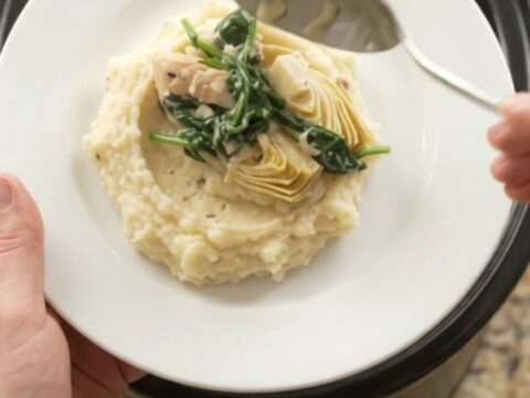 Slow cooker filled with creamy Swiss spinach artichoke chicken tenders, bubbling and steaming