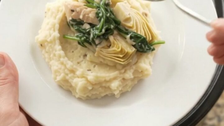 Slow cooker filled with creamy Swiss spinach artichoke chicken tenders, bubbling and steaming