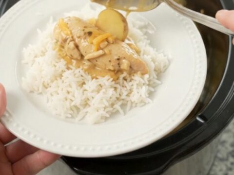 Slow cooker with golden cheddar chicken and potatoes, ready to serve