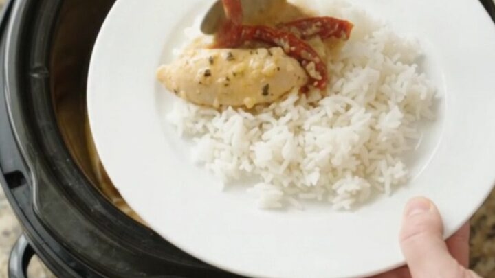 Slow cooker chicken tenders in golden cheddar sauce with sun-dried tomatoes, served over rice