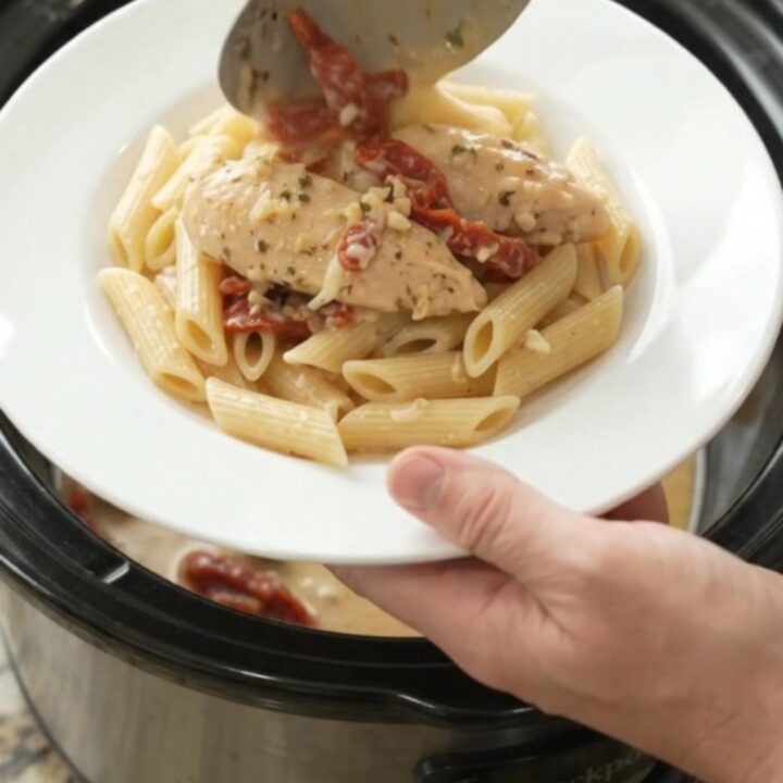 Slow cooker chicken tenders in creamy mozzarella sauce with sun-dried tomatoes, in a black crockpot
