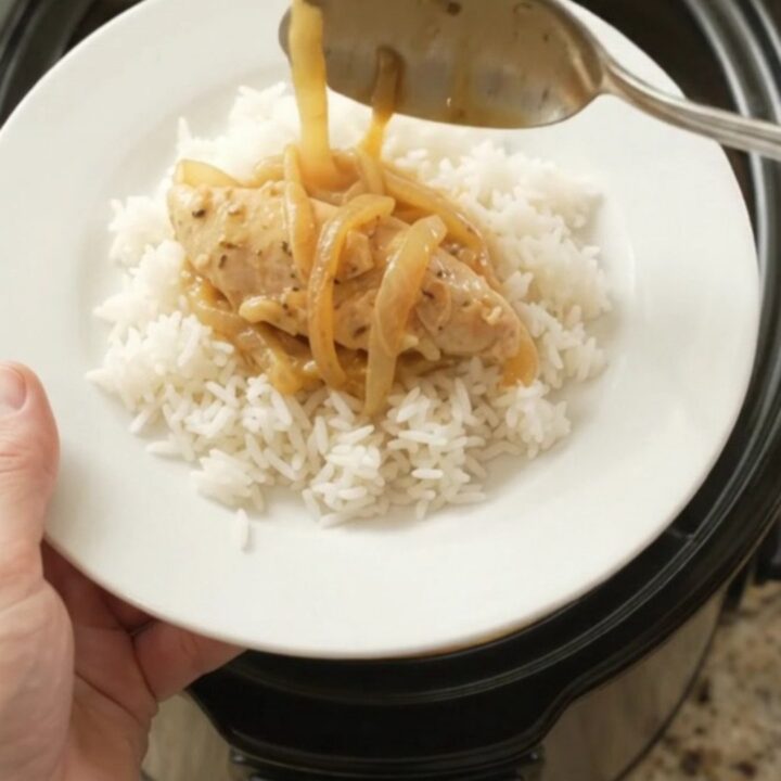 Golden cheddar French onion chicken tenders bubbling in a slow cooker with melted cheese and caramelized onions