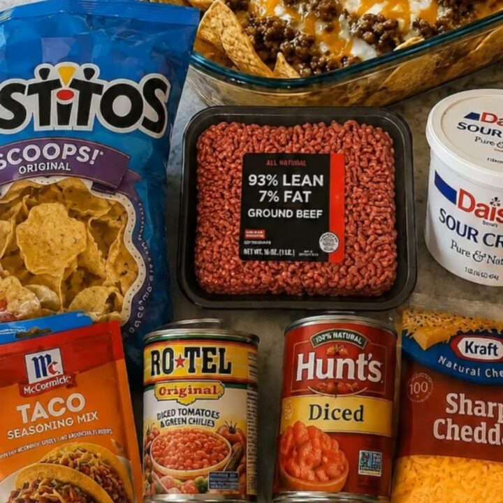 A glass baking dish filled with a loaded beef nacho bake, featuring melted cheddar, seasoned beef, and fresh toppings.