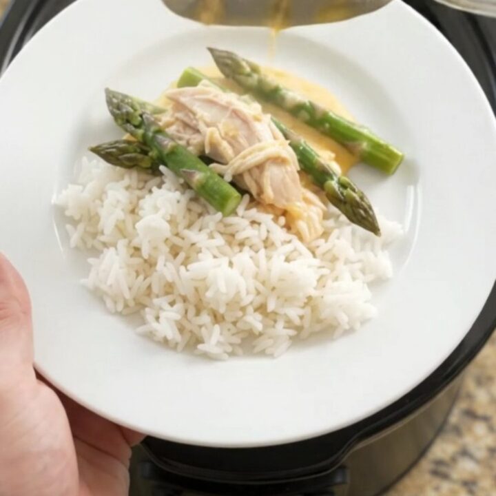 Slow cooker filled with creamy turkey, asparagus, and melted cheddar cheese