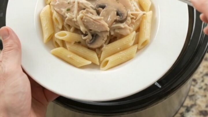Slow cooker full of creamy turkey and mushrooms with melted mozzarella