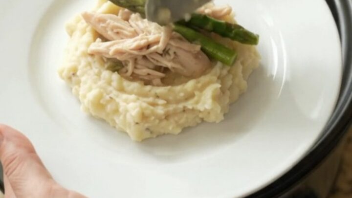 Slow cooker filled with creamy Swiss asparagus turkey breast, topped with melted cheese and sour cream sauce.