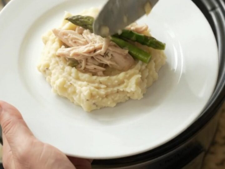 Slow cooker filled with creamy Swiss asparagus turkey breast, topped with melted cheese and sour cream sauce.