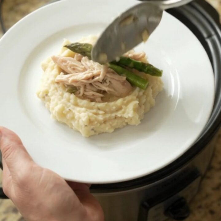 Slow cooker filled with creamy Swiss asparagus turkey breast, topped with melted cheese and sour cream sauce.