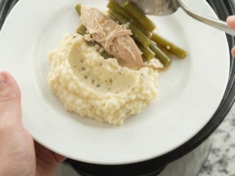 Slow cooker creamy Swiss green bean turkey breast in a black Crockpot, bubbling and steamy