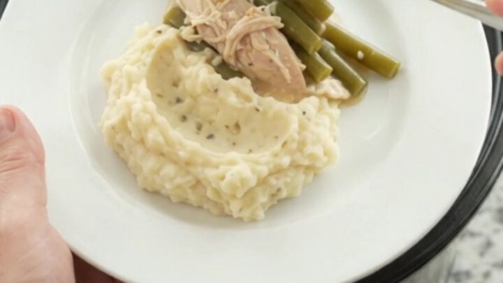 Slow cooker creamy Swiss green bean turkey breast in a black Crockpot, bubbling and steamy