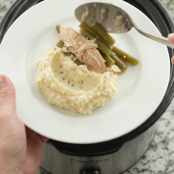 Slow cooker creamy Swiss green bean turkey breast in a black Crockpot, bubbling and steamy