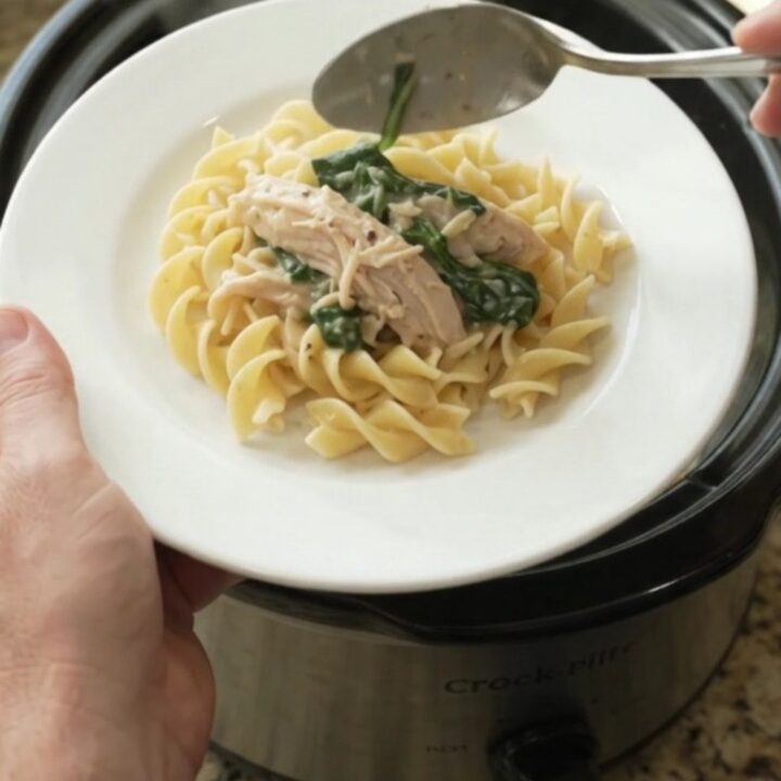 Creamy slow cooker turkey with spinach and artichokes in a white bowl, topped with Parmesan