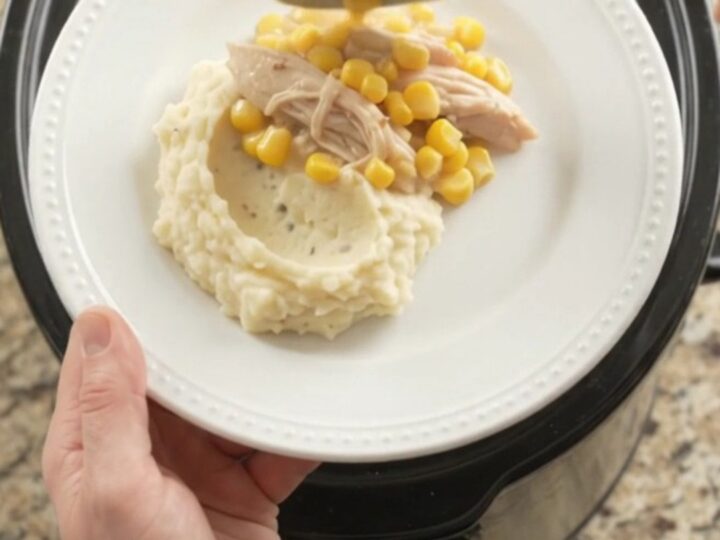 Slow cooker turkey breast with creamy Swiss corn sauce, served on a plate with mashed potatoes.