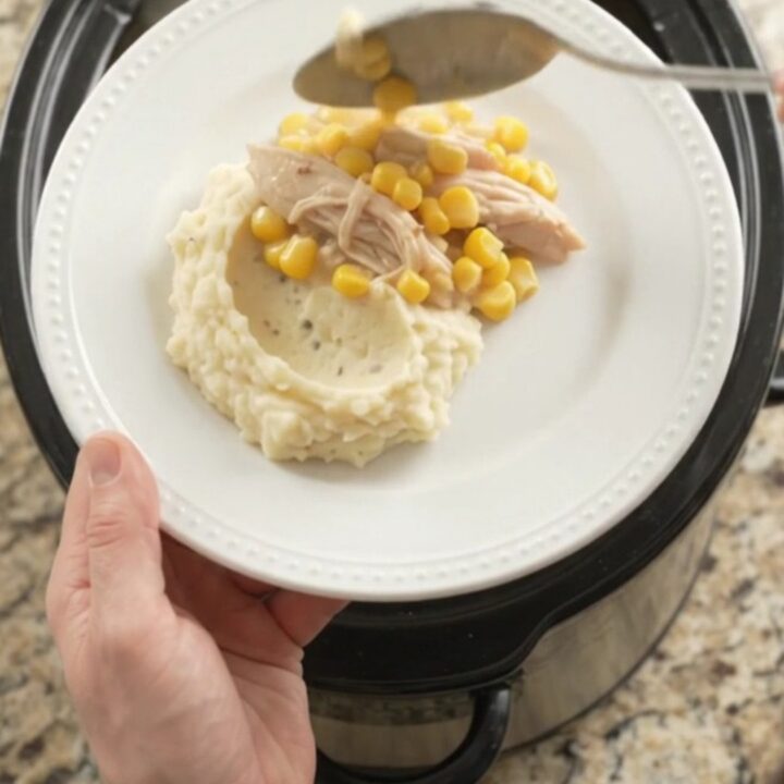 Slow cooker turkey breast with creamy Swiss corn sauce, served on a plate with mashed potatoes.