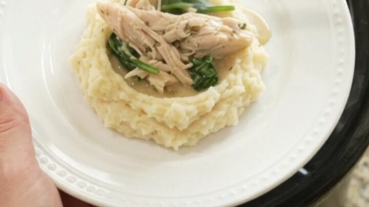 Creamy Swiss turkey with spinach and artichokes in a slow cooker, garnished with fresh herbs