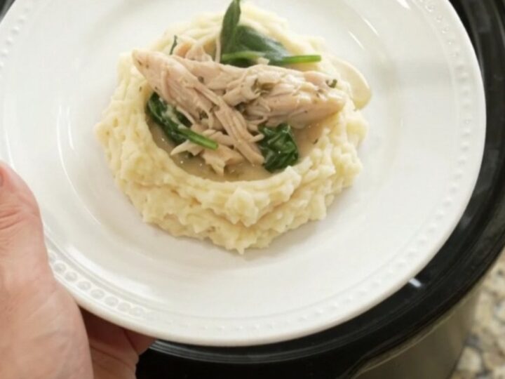 Creamy Swiss turkey with spinach and artichokes in a slow cooker, garnished with fresh herbs