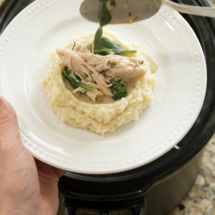 Creamy Swiss turkey with spinach and artichokes in a slow cooker, garnished with fresh herbs