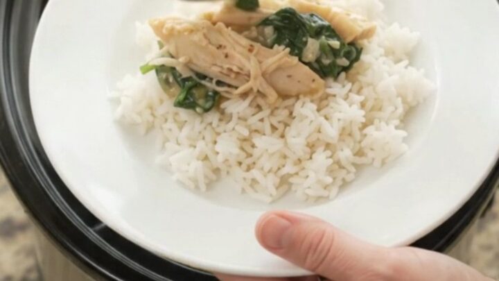 Slow cooker filled with creamy shredded turkey, spinach, artichokes, and melted cheddar cheese