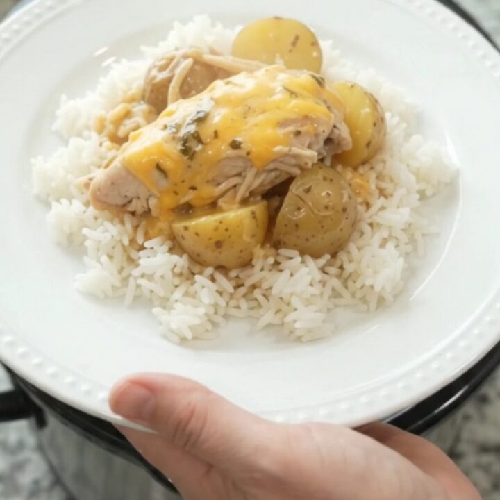 Creamy slow cooker turkey and potatoes with melted cheddar in a black crock