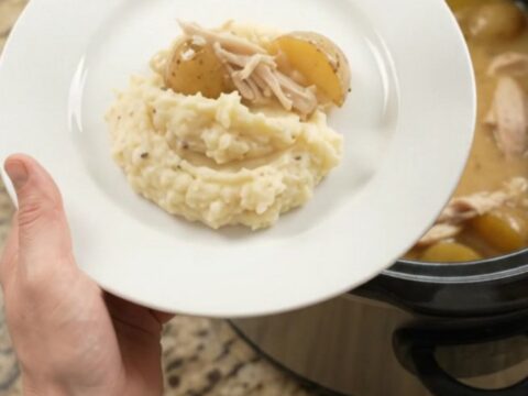 Slow cooker with creamy Swiss turkey and baby potatoes, bubbling sauce, top view