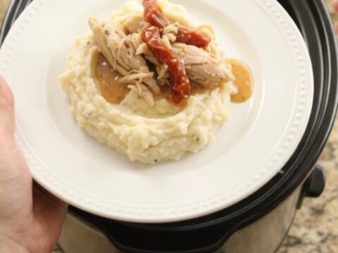 Creamy slow cooker turkey breast with sun-dried tomatoes and Swiss cheese sauce in a black crockpot