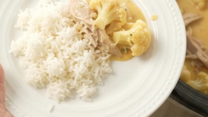 Slow cooker filled with creamy cheddar turkey and cauliflower, topped with melted cheese and butter.