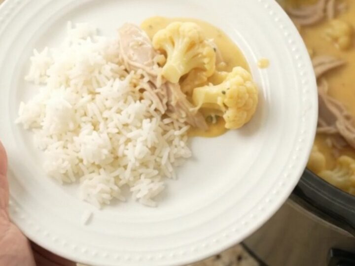 Slow cooker filled with creamy cheddar turkey and cauliflower, topped with melted cheese and butter.