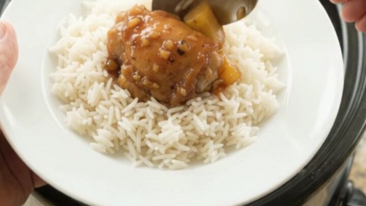 Slow cooker full of caramelized chicken thighs and pineapple chunks in a sticky glaze