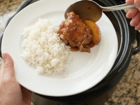 Slow cooker full of peach hickory BBQ chicken thighs, caramelized and glistening