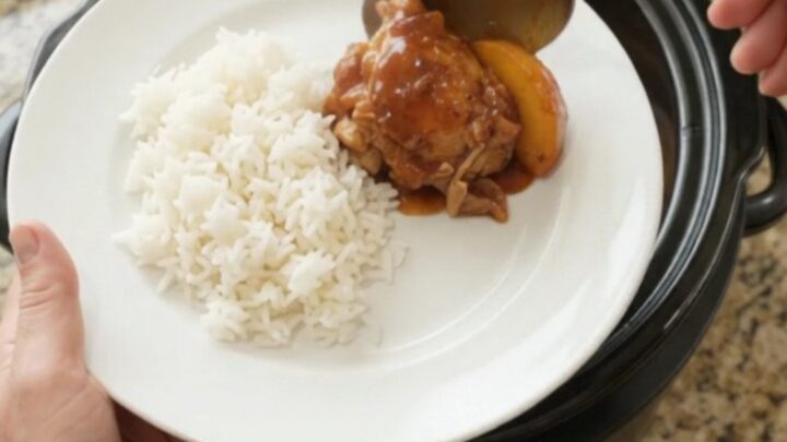 Slow cooker full of peach hickory BBQ chicken thighs, caramelized and glistening