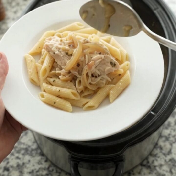 Slow cooker filled with shredded turkey, onions, and melted mozzarella in a creamy sauce