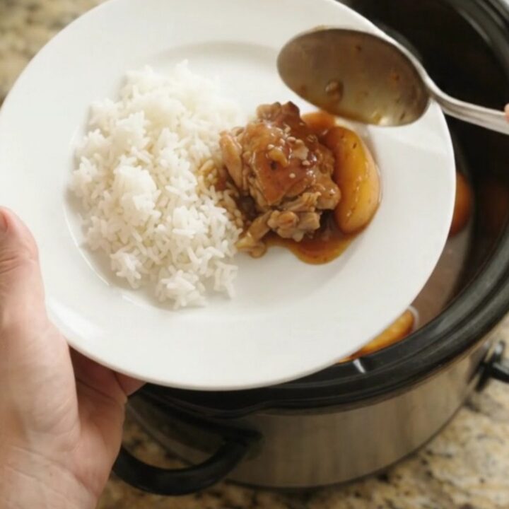 Slow cooker with caramelized peach teriyaki chicken thighs, glistening sauce, sesame seeds