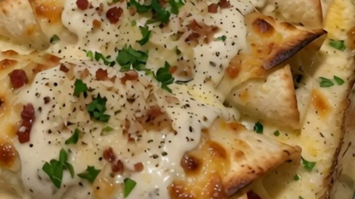 A golden-brown chicken bacon alfredo wrap with a visible cheese pull being lifted from a baking dish.