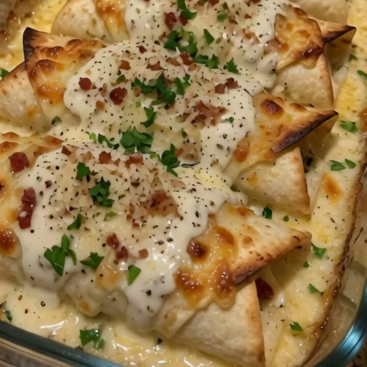 A golden-brown chicken bacon alfredo wrap with a visible cheese pull being lifted from a baking dish.