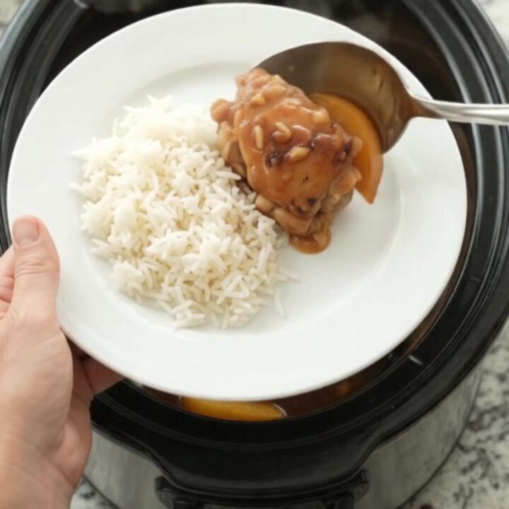 Slow-cooked chicken thighs glazed with honey-soy sauce and peaches in a black Crockpot