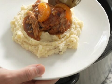 Slow cooker full of glazed chicken thighs with mandarin oranges and bourbon sauce, ready to serve